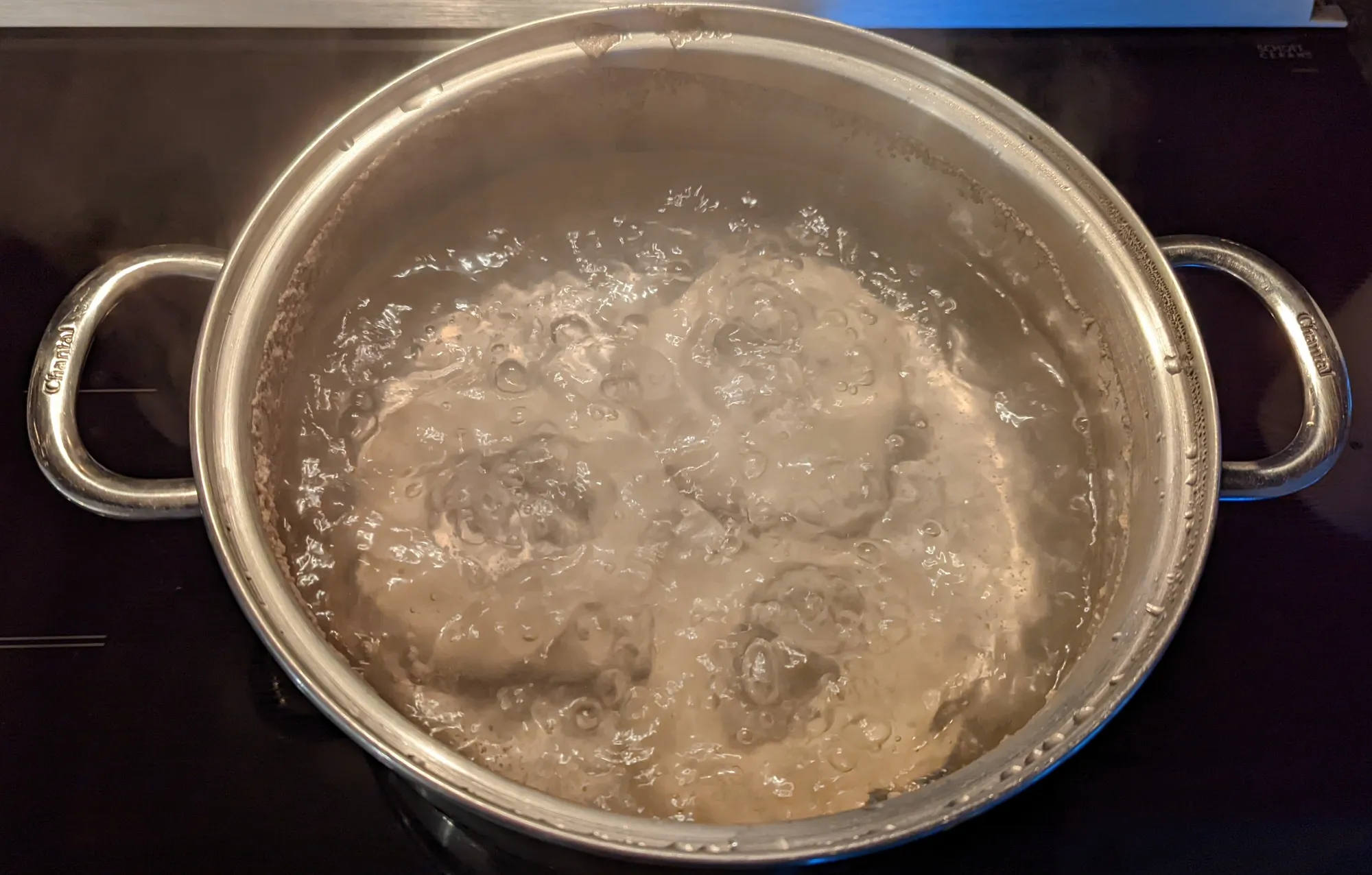 3 bagels simmering in a pot of brine.